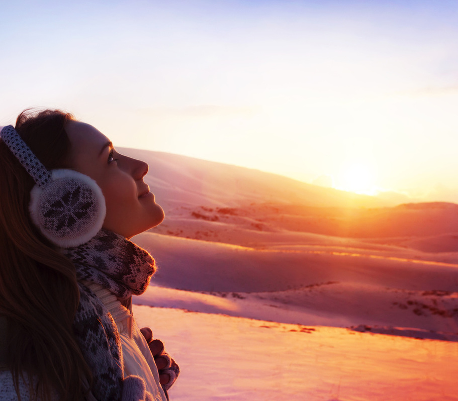 Young woman in mountain snow field enjoying winter sunset